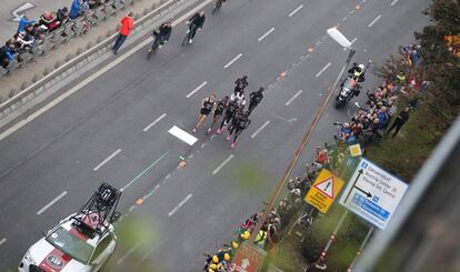 Según los cálculos del equipo de Kipchoge, el trabajo de las liebres y el rebufo del vehículo que abre la carrera han supuesto un minuto y 40 segundos más de beneficio. En la imagen, Kipchoge y el grupo de atletas corren detrás del coche que marca los tiempos, este sábado en Viena.