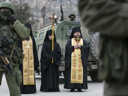 Sacerdotes ortodoxos rezam perto de soldados russos na Balaclava (Crimeia).