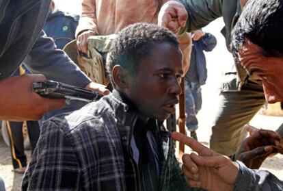 Foto: Rebeldes interrogan, arma en mano, a un sospechoso de ser partidario de Gadafi, entre las localidades de Brega, núcleo de los combates, y Ras Lanuf.