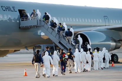 Imigrantes venezuelanos e colombianos são deportados com equipamentos de proteção contra a covid-19, no aeroporto de Iquique, Chile, nesta quarta-feira.