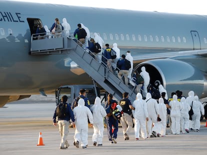Imigrantes venezuelanos e colombianos são deportados com equipamentos de proteção contra a covid-19, no aeroporto de Iquique, Chile, nesta quarta-feira.