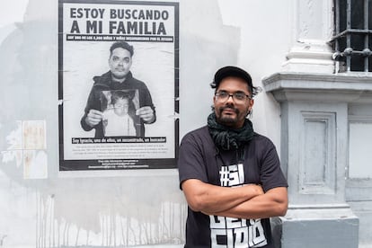 Ignacio 'Nacho' Alvarado posa frente al cartel del colectivo 'Estamos Aquí' y de la búsqueda de su familia, en Ciudad de Guatemala el 5 junio de 2023.