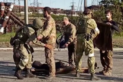 Foto tomada de un vídeo publicado por el Servicio de Prensa del Ministerio de Defensa de Rusia el martes 17 de mayo de 2022, que muestra a soldados rusos cacheando a soldados ucranios mientras son evacuados de la planta siderúrgica Azovstal.