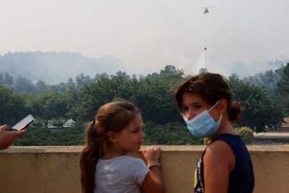 Dos niños observan como un helicóptero sobrevuela el incendio forestal en Xerta (Tarragona), este martes.