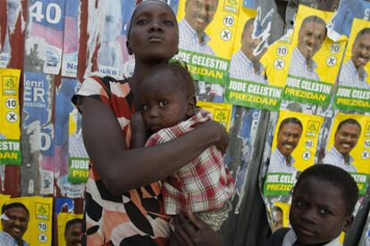 Una mujer haitiana con sus dos hijos, ante carteles electorales en Petionville.