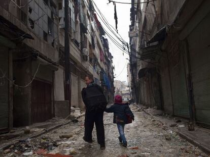 Dos transe&uacute;ntes caminan por una desierta calle de Alepo. 