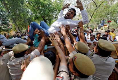 Un activista del Congreso Juvenil de Pradesh de Delhi grita consignas cuando varios policía intentan impedirle cruzar una barricada durante una protesta contra la subida de impuestos, en Nueva Delhi.
