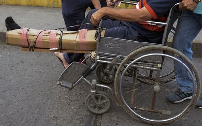 Un hombre en silla de ruedas, con una escayola improvisada elaborada con cartones, cruza el puente Simón Bolívar hacia Cúcuta (Colombia), el miércoles.