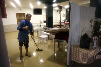 Un hombre limpia un restaurante afectado por las fuertes lluvias en Lorca (Murcia), este jueves.