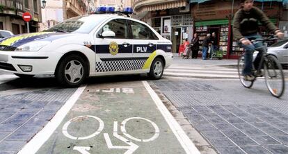 Un coche de la Policía Local cruzado sobre el carril bici en una calle de Valencia.