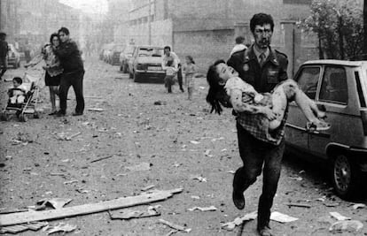 Un agente de la Guardia Civil ensangrentado lleva en brazos a una niña herida en el atentado contra la Casa Cuartel de Vic, en 1991. 