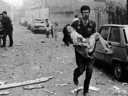 Un agente de la Guardia Civil ensangrentado lleva en brazos a una niña herida en el atentado contra la Casa Cuartel de Vic, en 1991. 