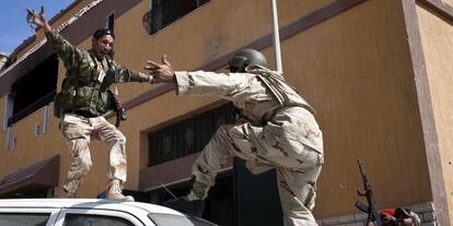 Dos rebeldes libios se abrazan celebrando la ca&iacute;da de la ciudad y la muerte de Muamar el Gadafi