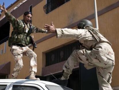 Dos rebeldes libios se abrazan celebrando la ca&iacute;da de la ciudad y la muerte de Muamar el Gadafi