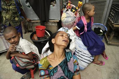 Una vecina llora sentada en la calle con sus pertenencias durante el incendio que se propaga por el suburbio en Ambagan (Bangladesh).