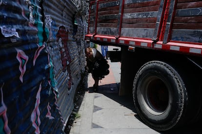 Una mujer pasa bajo de un camión atravesado sobre el paso peatonal, al sur de Bogotá.