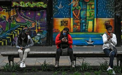 Tres mujeres revisan su móvil en una calle en Bogotá, este martes.