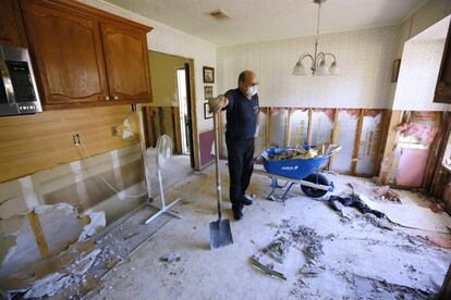 Un hombre toma un descanso mientras limpia la cocina de su casa, tras la inundación, en Prairieville, Luisiana (EE.UU).