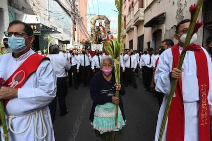 Una mujer camina por las calles de Tegucigalpa, Honduras, con una palma de coyol, planta autóctona de la región.