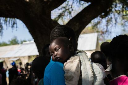 Un bebé duerme sobre el hombro de su madre mientras esta espera bajo un árbol a recibir el suplemento nutricional para su hjio en las afueras del hospital de MSF en Leer.