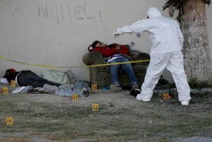 Un forense de la policía mexicana examina los cuerpos de dos hombres asesinados por el <i>narco</i> en las afueras de Monterrey.