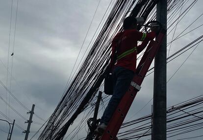 A lineman works on an electric post in Makati city, Metro Manila, Philippines, 24 July 2023.