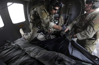 Dos militares estadounidenses depositan el cadáver de un soldado muerto en una bolsa para trasladarlo, el jueves en Kandahar.