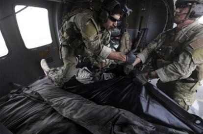 Dos militares estadounidenses depositan el cadáver de un soldado muerto en una bolsa para trasladarlo, el jueves en Kandahar.