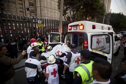 Miembros de la Cruz Roja meten dentro de una ambulancia a uno de los heridos por la explosión en la sede de Pemex.