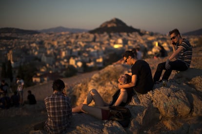 Un grupo de j&oacute;venes observa Atenas desde una colina al atardecer. 