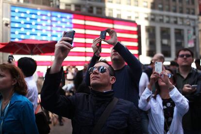 Viandantes en Times Square fotografan el momento de la salida de Facebook en la bolsa.