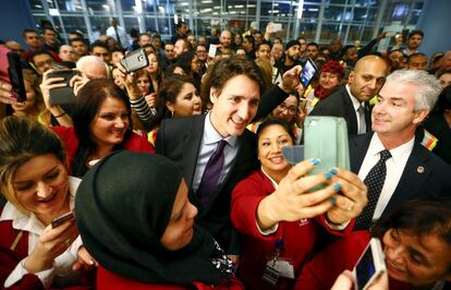 Canada's Prime Minister Justin Trudeau poses with airport staff as they await Syrian refugees to arrive at the Toronto Pearson International Airport in Mississauga, Ontario, December 10, 2015.  After months of promises and weeks of preparation, the first planeload of Syrian refugees was headed to Canada on Thursday, aboard a military plane to be met at Toronto's airport by Trudeau.   REUTERS/Mark Blinch 
