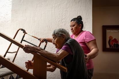 María Luisa Torres sube a su habitación asistida por una cuidadora.