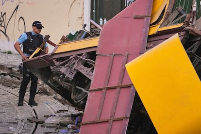 Un agente de policía inspeccionan el lugar donde el tranvía turístico descarriló y chocó contra un edificio, este jueves en Lisboa.