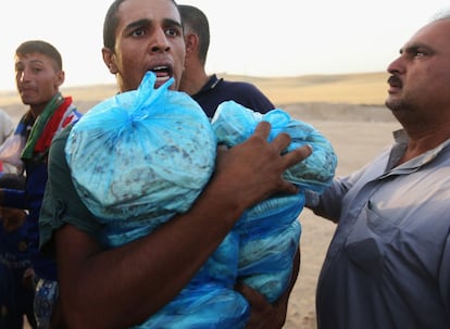 Un hombre iraquí que huyó de Mosul recoge paquetes de comida repartidos por una organización caritativa kurda en un campamento en la zona de Khazer, al norte de Irak. 29 de junio de 2014.