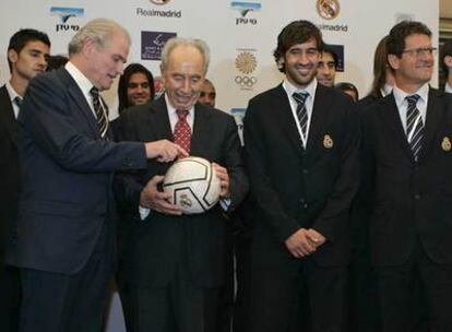 Simón Peres señala un balón del Madrid junto al presidente del club, Ramón Calderón, el capitán Raúl y Fabio Capello.