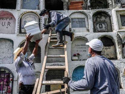 Un familiar de una víctima del conflicto armado colombiano entrega la urna con los restos de sus seres queridos a un sepulturero en el cementerio de Dabeiba (Colombia).