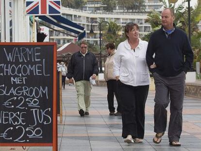 Dos turistas caminan por el paseo mar&iacute;timo de Torremolinos. 