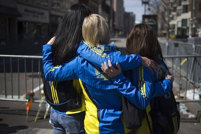 Tres mujeres que corrieron el Maratón de Boston se abrazan en la entrada de la calle Boylston, cerca del lugar de las explosiones.