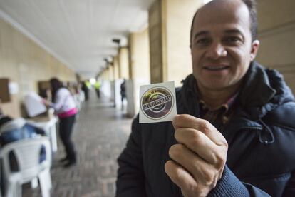 Un miembro del jurado de votación muestra la pegatina con la que se les identifica.