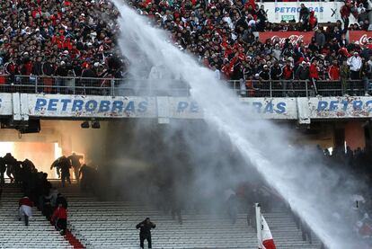 Los agentes tratan de repeler con agua a los hinchas furibundos.