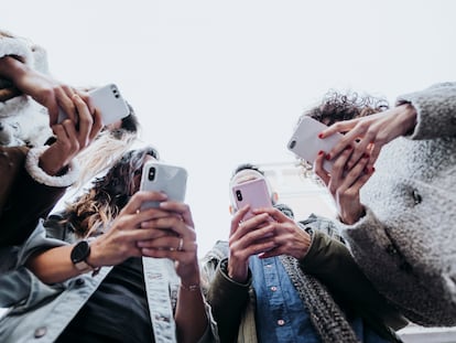 Cuatro amigos usan sus teléfonos móviles en la calle.