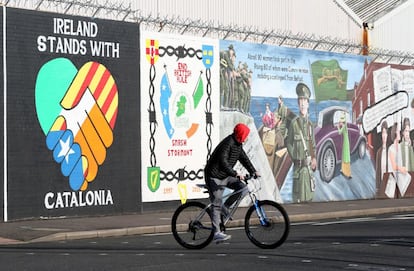 Un ciclista pasa junto a un mural pintado en apoyo a la independencia de Cataluña, en Belfast (Irlanda del Norte).