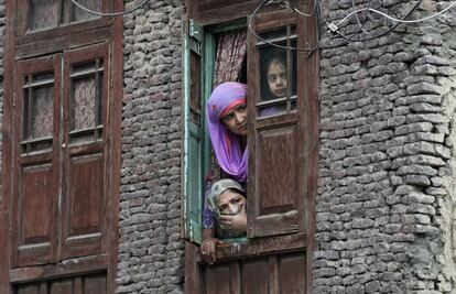 Residentes locales observan desde la ventana un enfrentamiento con armas de fuego, entre dos presuntos militantes y personal de las fuerzas gubernamentales indias, en el centro de Srinagar.