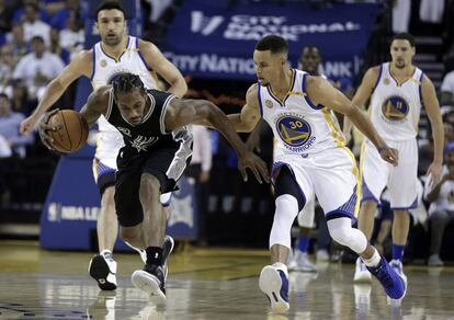 Kawhi Leonard protege a bola enquanto é marcado por Stephen Curry.