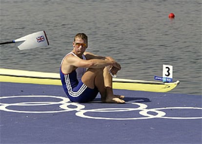 El británico Mathew Pinsent espera tranquilamente sentado para subir al podio y recibir su cuarto oro olímpico.