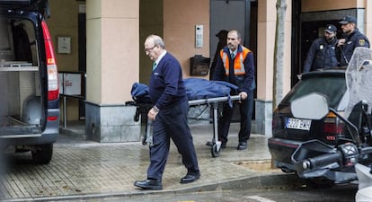 Membres dels serveis funeraris traslladen el cadàver de la dona.