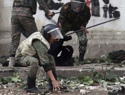 Miembros de la policía militar arrestan a un mujer cubierta con el 'niqab' (túnica que solo deja al descubierto los ojos) durante los enfrentamientos cerca de la plaza de Tahrir, en El Cairo.