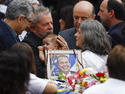 Lula segura no colo o filho mais novo de Eduardo e Renata Campos. O político do PSDB José Serra (ao fundo) os acompanha.