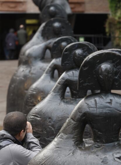 Un hombre fotografía las meninas de Manolo Valdés delante del CaixaForum.